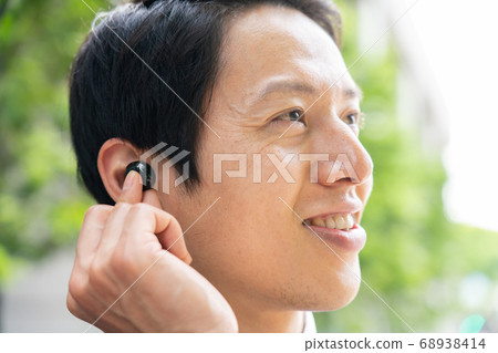 Businessman watching content with wireless earphones Businessman watching content with wireless earphones 68938414