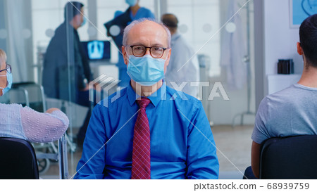 Senior man looking at camera in hospital waiting area Senior man looking at camera in hospital waiting area 68939759