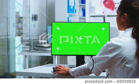 Doctor sits at computer with blank display 68939920