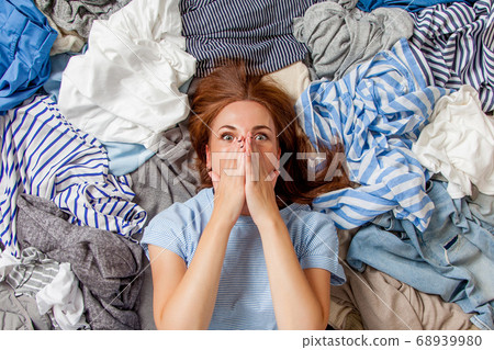 Beautiful caucasian woman smiling and lying down with clutter clothes on the floor. 68939980