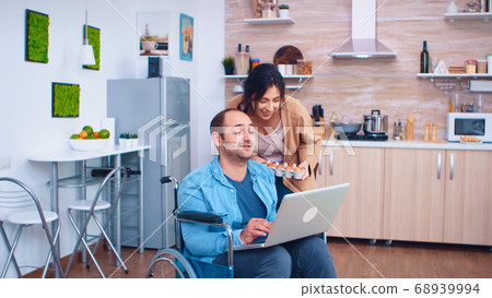 Disabled man in wheelchair using laptop 68939994