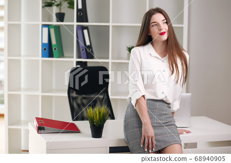 Happy businesswoman leaning on desk in office, office europe 68940905