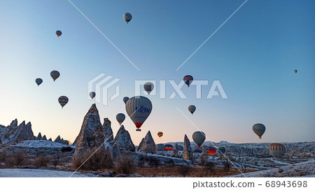 Colorful hot air balloons flying over the valley with fairy chimneys in winter season. Lots of Hot air balloons at the sunrise sky landscape in Cappadocia, Turkey Colorful hot air balloons flying over the valley with fairy chimneys in winter season. Lots of Hot air balloons at the sunrise sky landscape in Cappadocia, Turkey 68943698