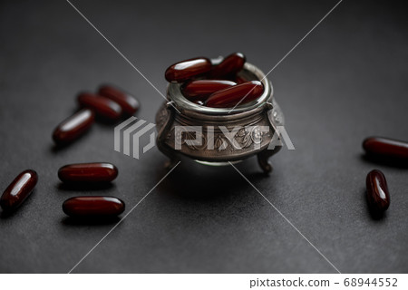 capsules with medicine in a silver bowl on a dark capsules with medicine in a silver bowl on a dark 68944552