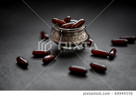 capsules with medicine in a silver bowl on a dark 68944556