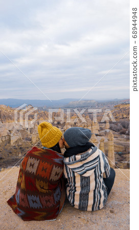 Travel couple watching mushroom shaped fairy chimneys at love valley in Cappadocia, Turkey. Happy couple watching the volcanic landscape at the valley of love in Goreme, Cappadocia Travel couple watching mushroom shaped fairy chimneys at love valley in Cappadocia, Turkey. Happy couple watching the volcanic landscape at the valley of love in Goreme, Cappadocia 68944948