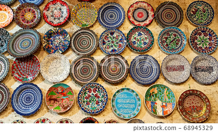 Hittite wine vessels, colorful ceramic vases and porcelain bowls in a underground cave atelier in Avanos in Cappadocia. Turkish traditional ceramic handycrafts in a local pottery shop in Cappadocia Hittite wine vessels, colorful ceramic vases and porcelain bowls in a underground cave atelier in Avanos in Cappadocia. Turkish traditional ceramic handycrafts in a local pottery shop in Cappadocia 68945329