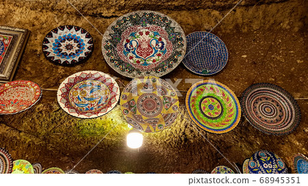 Hittite wine vessels, colorful ceramic vases and porcelain bowls in a underground cave atelier in Avanos in Cappadocia. Turkish traditional ceramic handycrafts in a local pottery shop in Cappadocia Hittite wine vessels, colorful ceramic vases and porcelain bowls in a underground cave atelier in Avanos in Cappadocia. Turkish traditional ceramic handycrafts in a local pottery shop in Cappadocia 68945351