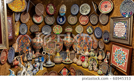 Hittite wine vessels, colorful ceramic vases and porcelain bowls in a underground cave atelier in Avanos in Cappadocia. Turkish traditional ceramic handycrafts in a local pottery shop in Cappadocia Hittite wine vessels, colorful ceramic vases and porcelain bowls in a underground cave atelier in Avanos in Cappadocia. Turkish traditional ceramic handycrafts in a local pottery shop in Cappadocia 68945353