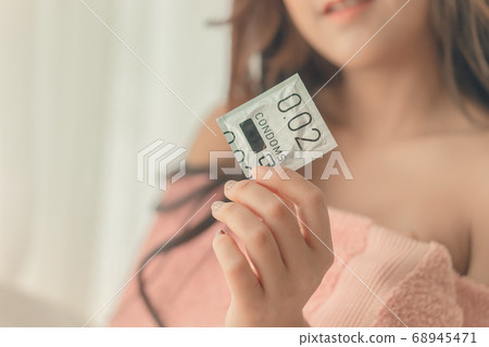 Happy girlfriend is holding a thing size condom 68945471