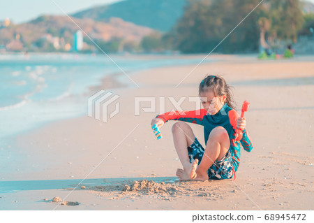 Little girl is playing with wave and sand on the Little girl is playing with wave and sand on the 68945472