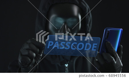 Hacker wearing black mask pulls PASSCODE tab from a smartphone. Hacking concept 68945556