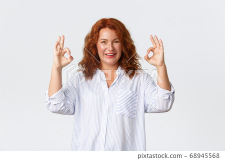 Confident smiling, lovely middle-aged redhead woman assure or guarantee everything under control, all good gesture, make okay sign, encourage or praise person, white background Confident smiling, lovely middle-aged redhead woman assure or guarantee everything under control, all good gesture, make okay sign, encourage or praise person, white background 68945568
