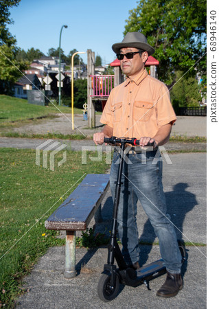 Taking a break in the park while moving on an electric scooter Vancouver British Columbia Canada Taking a break in the park while moving on an electric scooter Vancouver British Columbia Canada 68946140