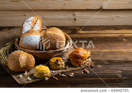 Bakery Assortment in basket on wooden table in dark background Bakery Assortment in basket on wooden table in dark background 68948705