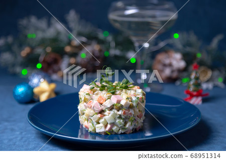Olivier salad on a blue plate, decorated with pea sprouts. Traditional New Year and Christmas Russian salad. 68951314