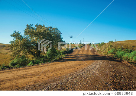 Deserted dirt road passing through rural lowlands 68953948