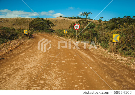 Dirt road on rural lowlands with dry hills 68954103