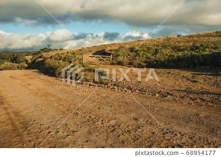 Wooden farm gate next to deserted dirt road Wooden farm gate next to deserted dirt road 68954177