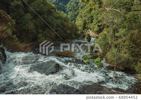 Waterfall falling over rocks in a lush forest Waterfall falling over rocks in a lush forest 68954452