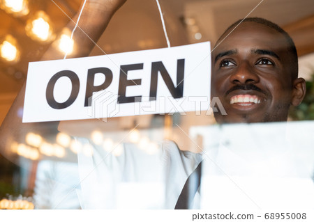 Happy young cafe worker hanging paper with notice open on transparent door Happy young cafe worker hanging paper with notice open on transparent door 68955008