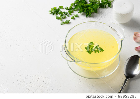 Chicken broth with green onion in white bowl on white table. Copy space. 68955285