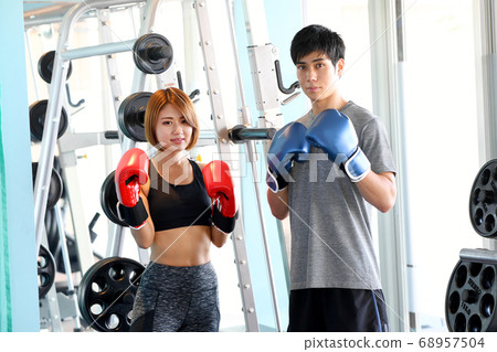 Men and women wearing gloves in a fighting pose at the gym 68957504
