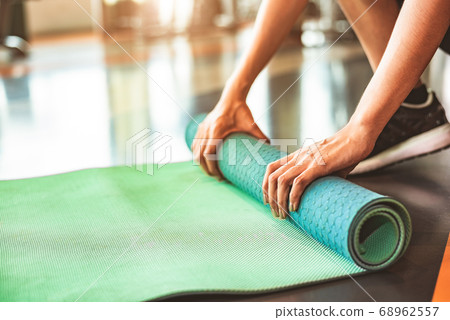 Close up of sporty woman folding yoga mattress in 68962557
