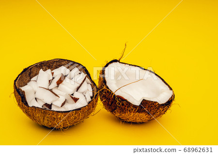 Parts of coconut on a colored background. Close up. Fresh ripe coconut broken into pieces. Parts of coconut on a colored background. Close up. Fresh ripe coconut broken into pieces. 68962631
