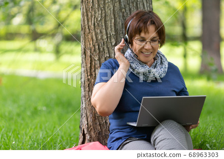 Close up portrait of a woman in city park having online conversation. Close up portrait of a woman in city park having online conversation. 68963303
