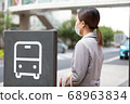 A woman waiting for a bus at the bus stop 68963834