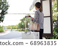 A woman waiting for a bus at the bus stop 68963835