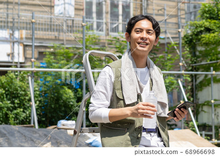 Young male worker using a smartphone at a construction site Young male worker using a smartphone at a construction site 68966698
