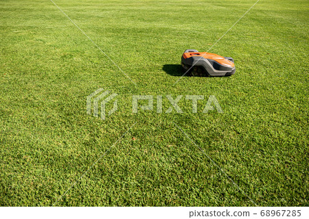 Automatic lawn mower robot moves on the green grass 68967285