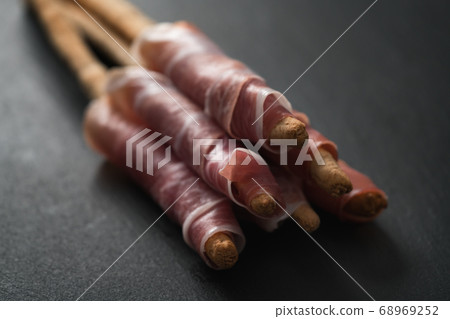 grissini breadsticks with prosciutto on slate background 68969252