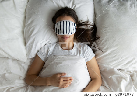 Top view peaceful young woman wearing mask sleeping in bed 68971078