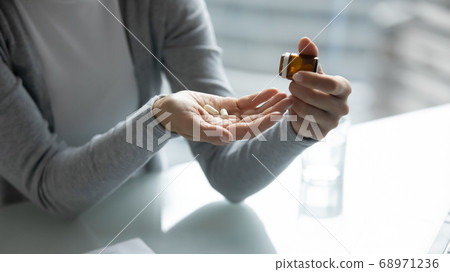 Close up young woman taking out pills from bottle Close up young woman taking out pills from bottle 68971236