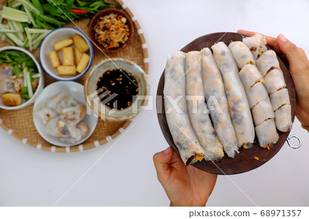 Vietnamese woman hand prepare breakfast, homemade vegan rice noodles roll from rice batter, delicious vegetarian stuffed dish Vietnamese woman hand prepare breakfast, homemade vegan rice noodles roll from rice batter, delicious vegetarian stuffed dish 68971357