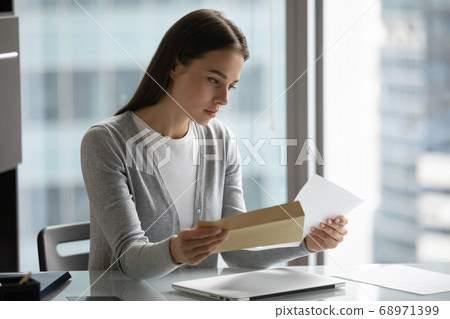 Serious confident businesswoman reading letter, holding open envelope 68971399