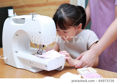 A girl who teaches sewing to mom A girl who teaches sewing to mom 68973536