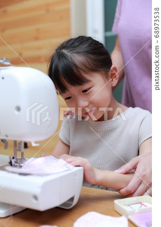 A girl who teaches sewing to mom A girl who teaches sewing to mom 68973538