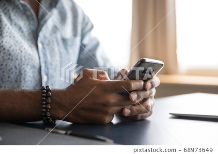 Close up African American man using phone, sitting at work desk Close up African American man using phone, sitting at work desk 68973649