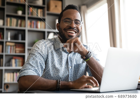 Head shot portrait laughing African American businessman sitting at desk Head shot portrait laughing African American businessman sitting at desk 68973680