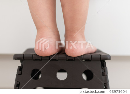 Feet of a young child who climbs on the platform and stretches out 68975604