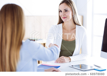Business woman headshot while shaking hands with her female colleague or client in office. Casual white clothes style of business people. Audit, tax or lawyer concept 68978080