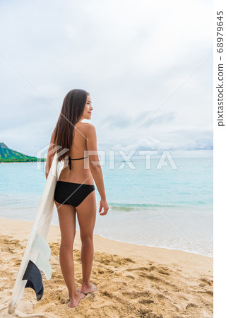 Surfing surfer girl looking at ocean beach. Female bikini woman waiting for waves with surfboard living healthy active hawaiian lifestyle. Surf model in waikiki city, Oahu, Hawaii, USA 68979645