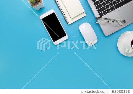 top view blue pastel office desk with computer, office supplies, cell phone, and black coffee cup 68980358
