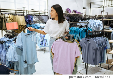 Woman holds clothes on hanger in clothing store 68981434