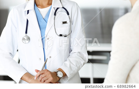 Unknown woman-doctor and patient in hospital. Blonde physician controls medication history records and exam results while using clipboard, close-up. Medicine concept Unknown woman-doctor and patient in hospital. Blonde physician controls medication history records and exam results while using clipboard, close-up. Medicine concept 68982664