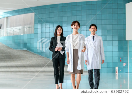 Medical image of female doctor and male and female medical staff walking through hospital hall Medical image of female doctor and male and female medical staff walking through hospital hall 68982792